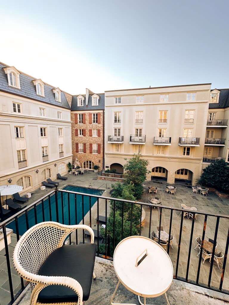 Quiet morning view from a historic French Quarter balcony in New Orleans – hidden courtyard pool, wrought-iron details and classic Creole architecture at golden hour